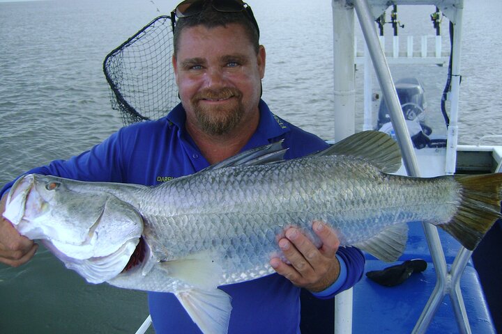 An angler holding a fish aboard a boat on choppy water