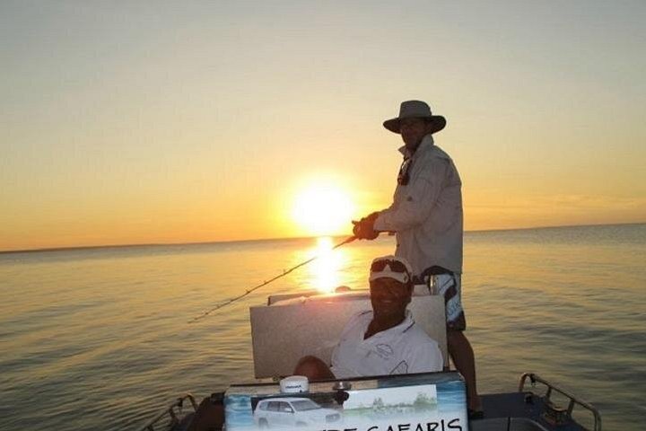 Two anglers with fishing rods on a boat in golden light